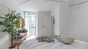 Un dormitorio minimalista con una cama, una planta en maceta y vistas al exterior.