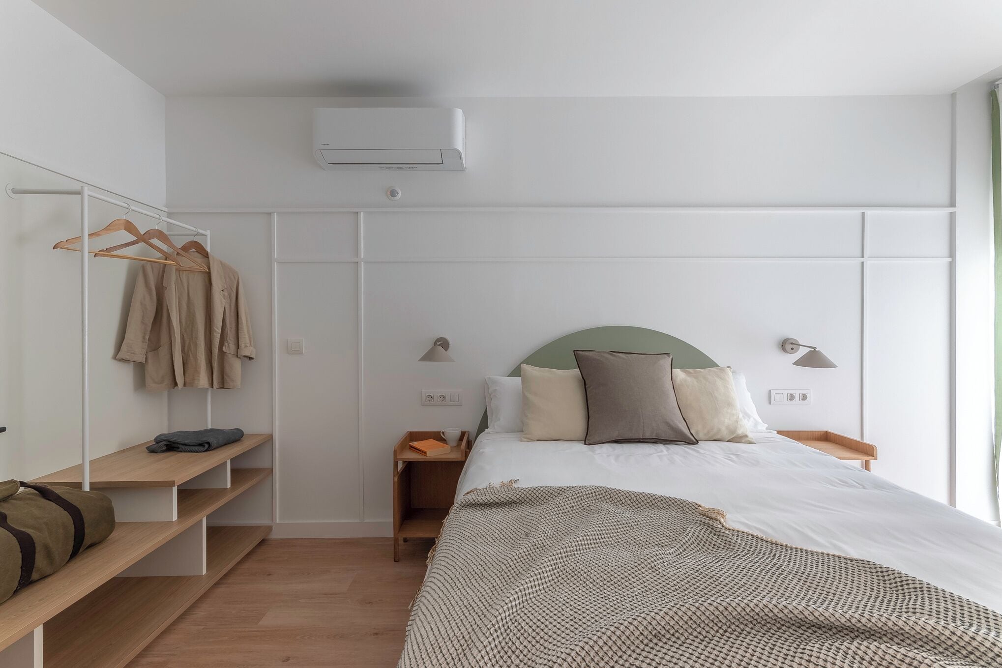 Un dormitorio con cama, mesitas de noche, armario y perchero.
