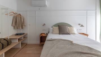 Un dormitorio con cama, mesitas de noche, armario y perchero.