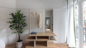 Habitación minimalista con un espejo grande, una planta y un banco.