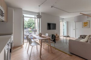 Un appartamento moderno con zona pranzo, divano, televisore e balcone vista strada.
