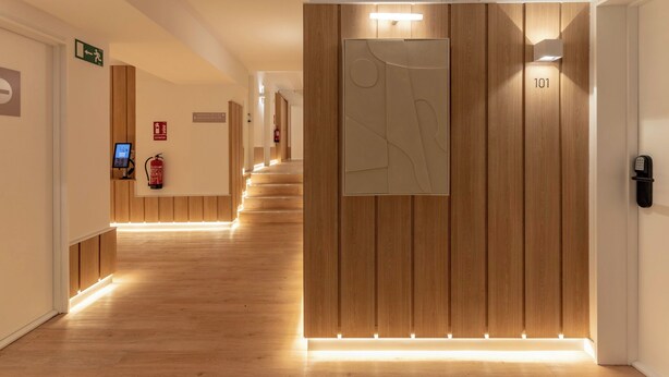 A modern hotel corridor with wooden paneling, a reception desk, and a fire extinguisher. - B48 Bilbao Abando (Bilbao)
