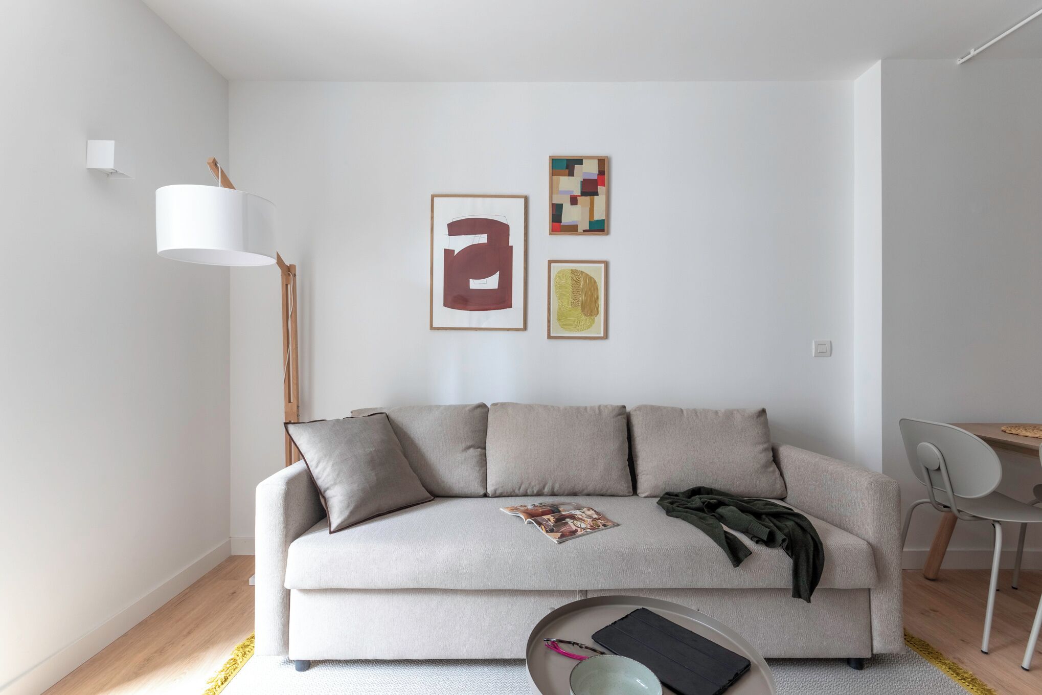 A modern living room with a sofa, a floor lamp, and wall art.
