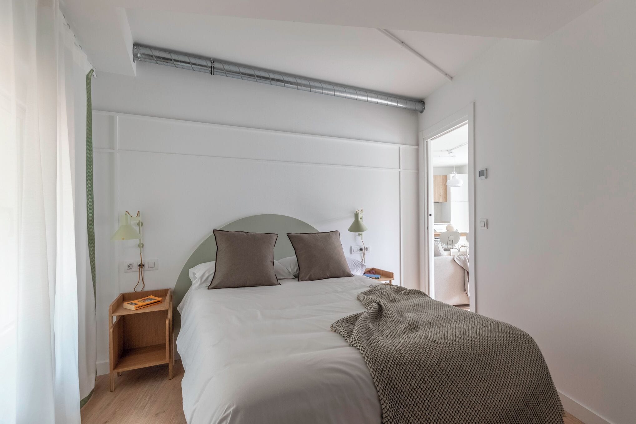 Une chambre à coucher avec un lit, des tables de chevet, une commode, une lampe et une vue sur la salle de bain.