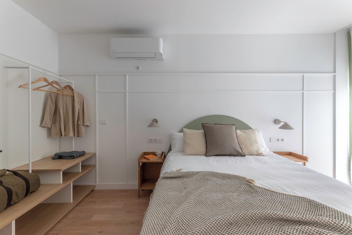 A bedroom with a bed, bedside tables, a wardrobe, and a hanging rack.