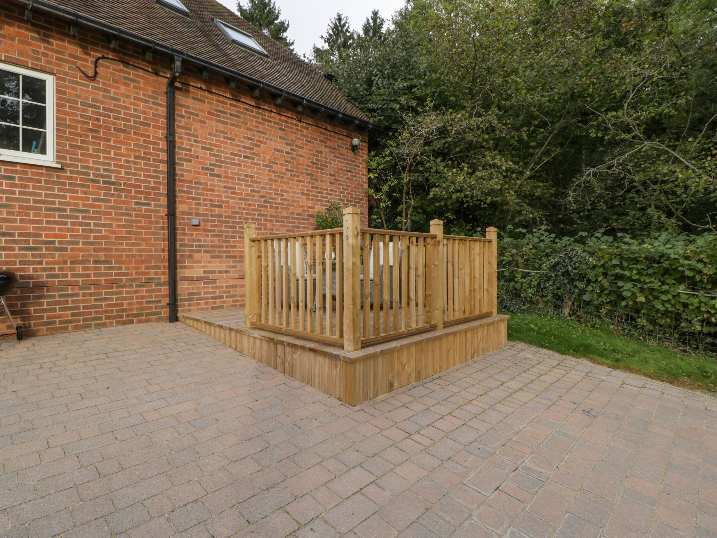 A brick house with a wooden deck and a paved driveway.