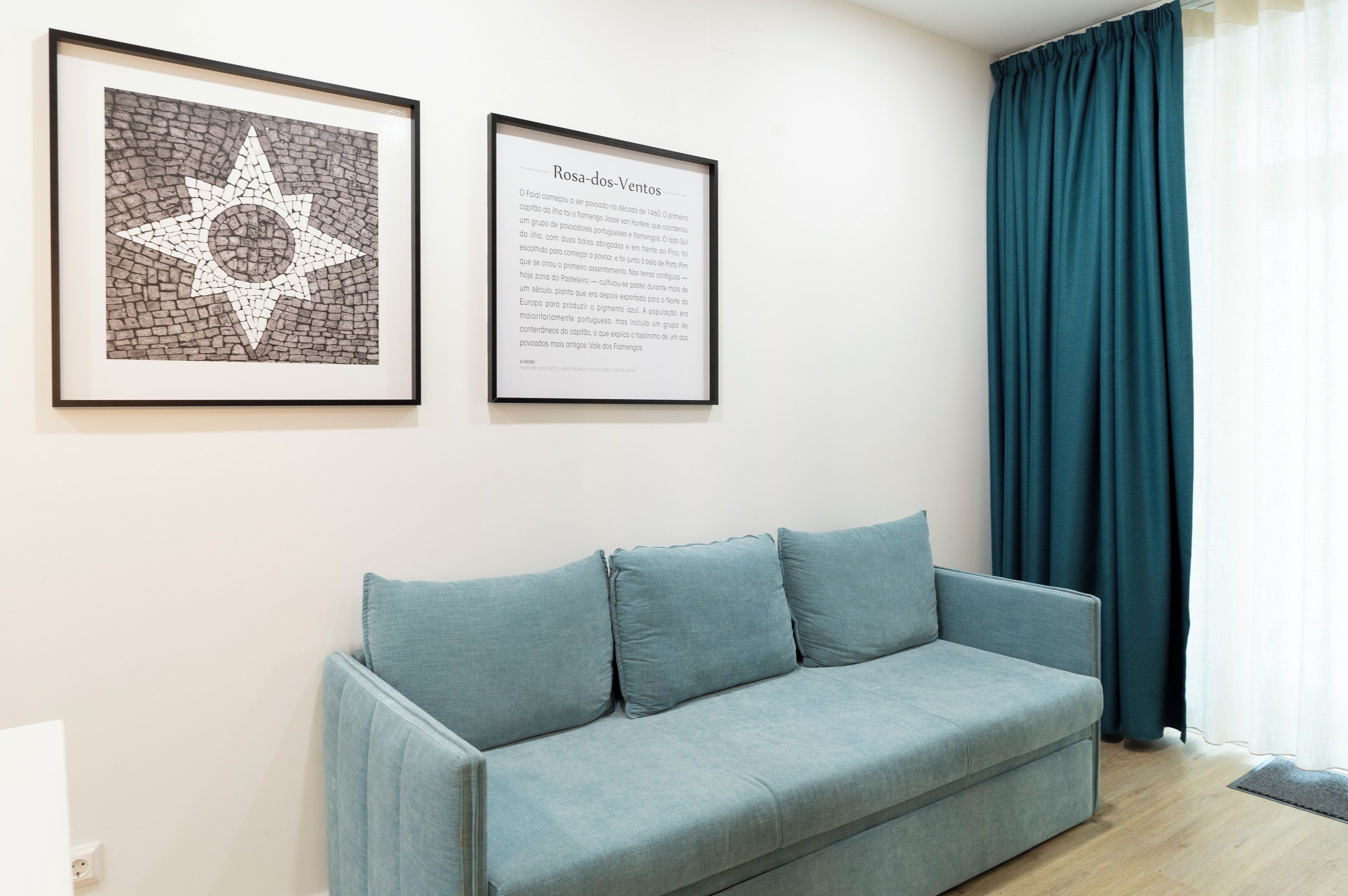 Ein Zimmer mit einem hellblauen Sofa, einem gerahmten Kunstwerk mit einem Stern und einem gerahmten Text an der Wand.