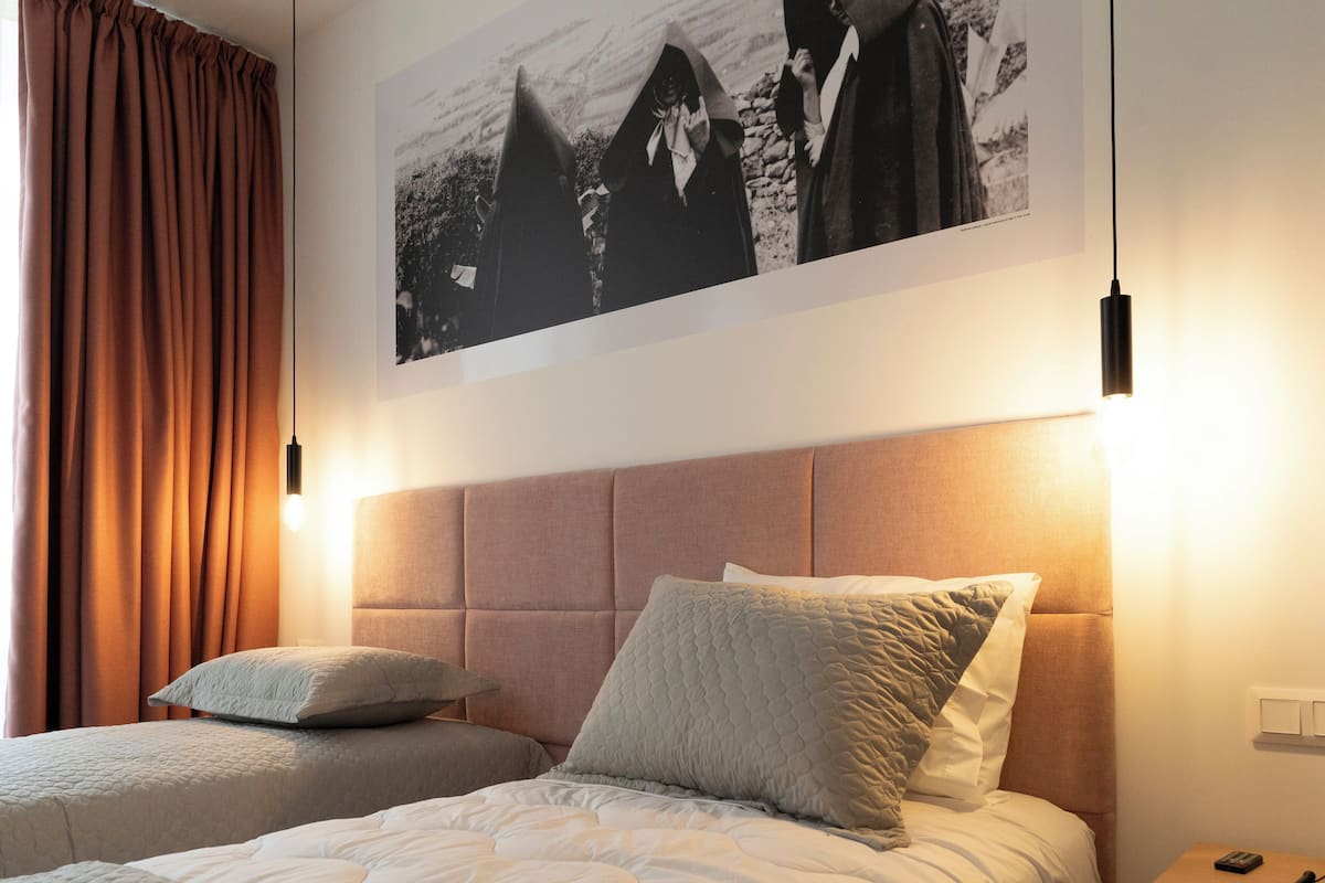 A hotel room with a large bed, two pillows, a headboard, and a framed picture on the wall.