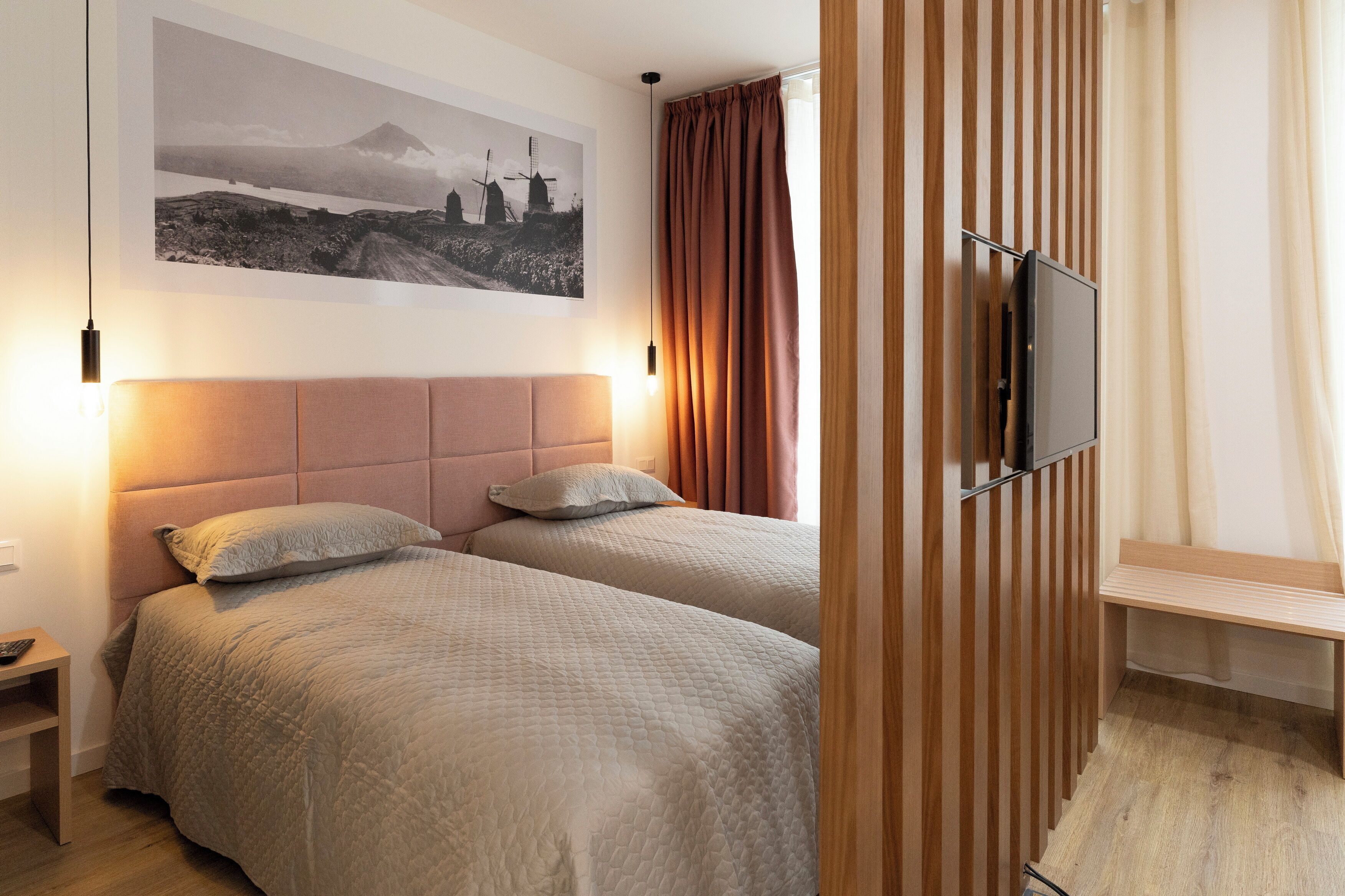 Ein Schlafzimmer mit zwei Betten, einem Fernseher und einer Holzwand.