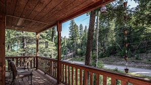 A wooden deck with a railing overlooking a forested area. - Woodlands Way Chalet- A cozy get-away in Cloudcroft NM.
 (Cloudcroft)
