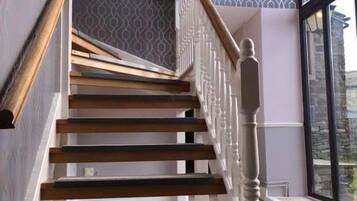 Una escalera de madera con balaustres blancos y un ventanal en la parte superior.