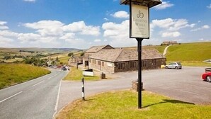 Entorno rural con un cartel que indica 'Leeming Welles' y un edificio de piedra.