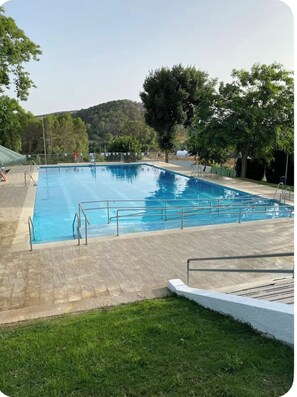Ein rechteckiger Pool mit Metallgeländern und einer gefliesten Terrasse rundherum.