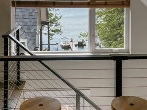A staircase with metal railings leading to a window overlooking a body of water with boats.