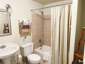 A bathroom with a sink, toilet, bathtub, and shower curtain. - Cozy room located in historic downtown with a 5 minute walk to the riverfront! (Louisiana)