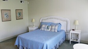 Une chambre à coucher avec un grand lit, deux tables de chevet et un ventilateur de plafond.