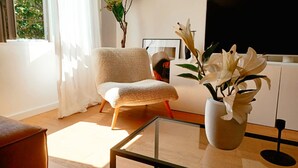 A modern living room with a plush armchair, a glass coffee table, and a potted white orchid. - Modern and Spacious apt Tanja With Private Parking (Split)