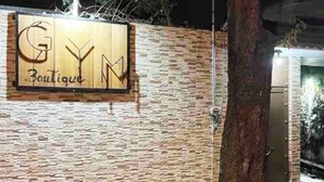 Un mur sur lequel est affiché un panneau indiquant « Gym Boutique », et le tronc d’un arbre.