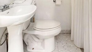 Une salle de bain avec un lavabo blanc, des toilettes et une serviette accrochée au mur.