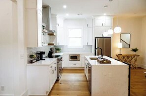 Enjoy cooking in this well-equipped kitchen with a central island, stainless steel appliances, and ample natural light.