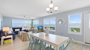 A spacious living room with a large window, a dining area, and a kitchen.