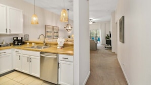 A modern kitchen with white cabinets, a coffee bar, and pendant lighting.