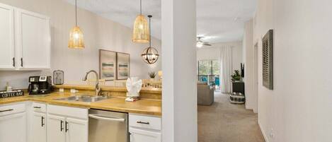 A modern kitchen with white cabinets, a coffee bar, and pendant lighting.