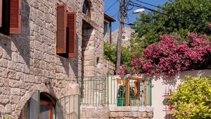 A stone building with a courtyard, featuring a table and chairs, a gate, and a staircase leading to an upper level. - Casa del Porto Suite- Intimate private suite (Byblos)