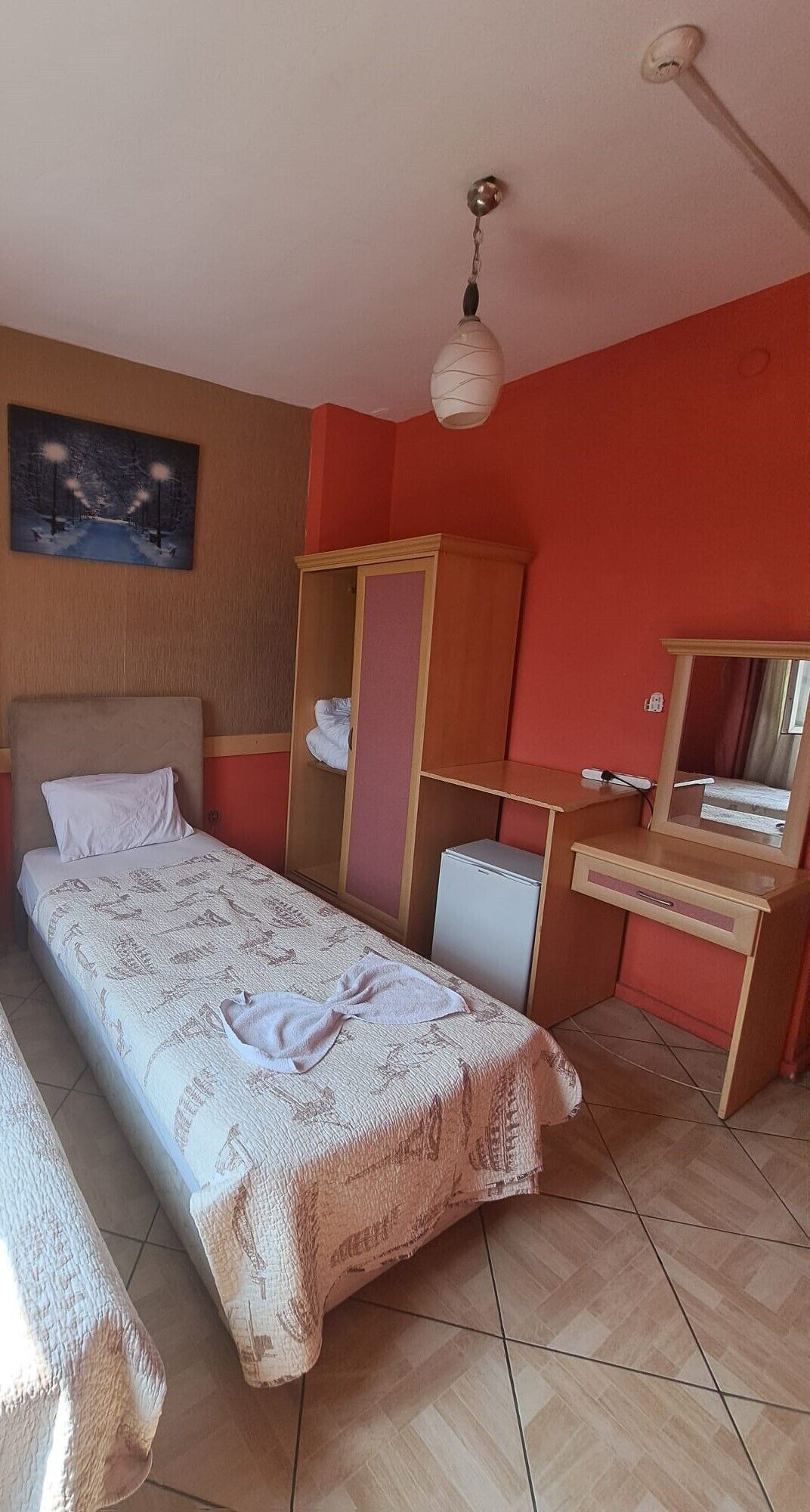A bedroom with a bed, a dresser, a mirror, and a painting on the wall.