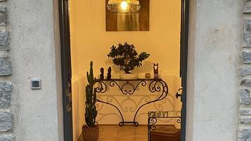 A hotel entrance with a wrought iron gate, a potted plant, a bench, and a welcome mat.