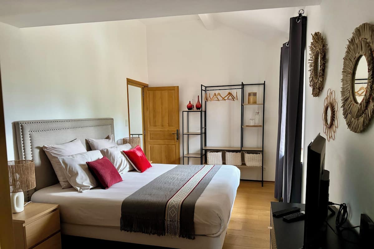 A bedroom with a bed, bedside tables, a TV, and a wardrobe.
