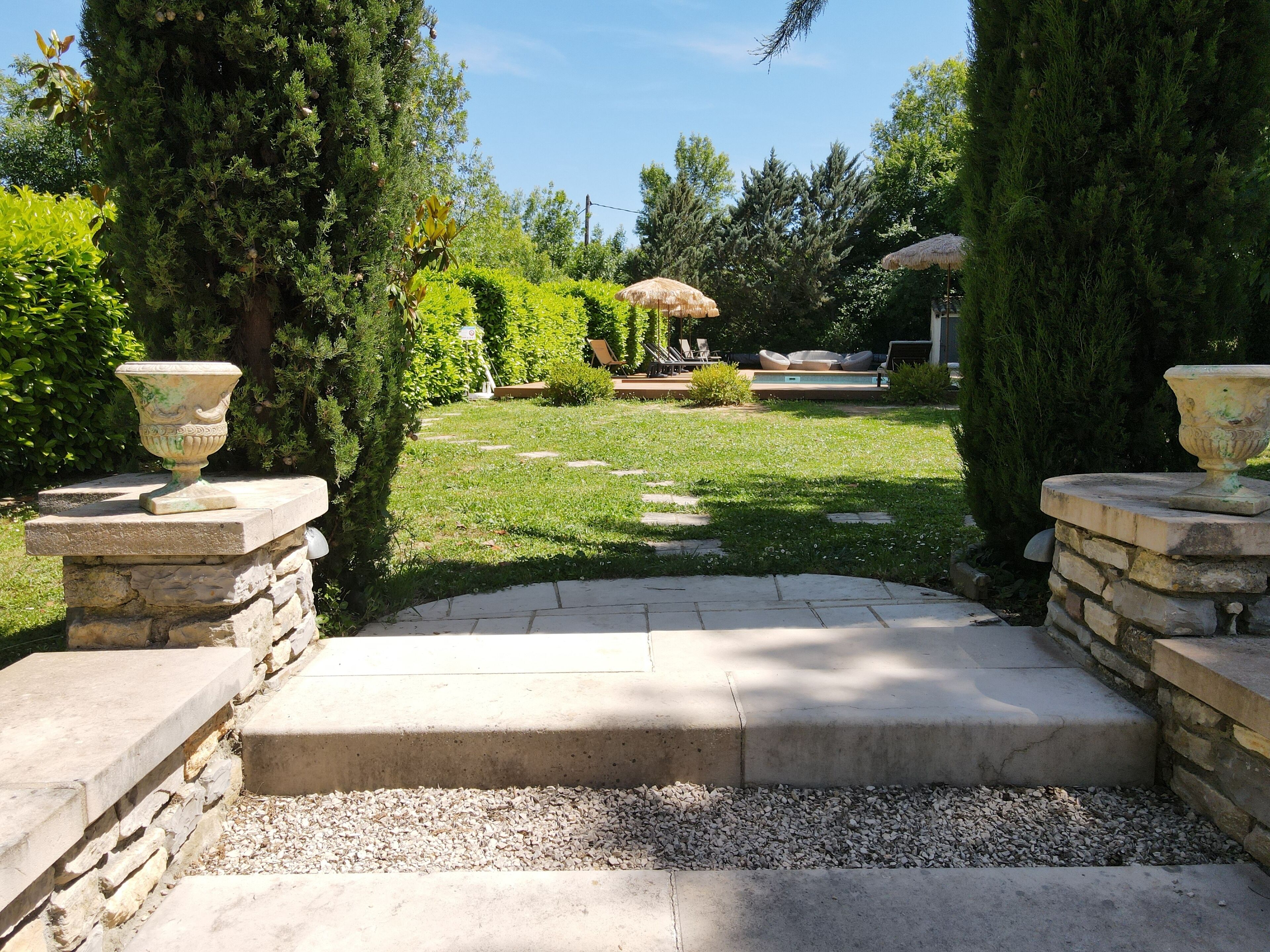 A stone pathway leading to a seating area with a pool and lounge chairs.
