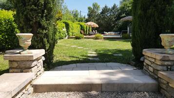 A stone pathway leading to a seating area with a pool and lounge chairs.