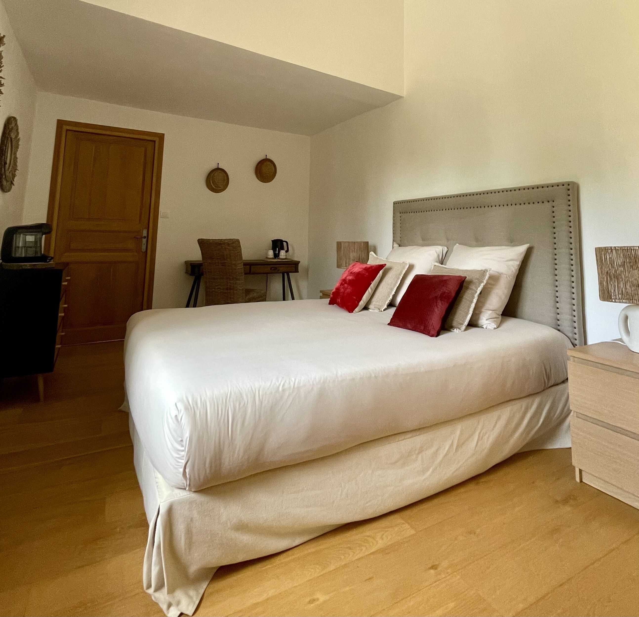 A neatly arranged bedroom with a large bed, a wooden desk, and a chair.