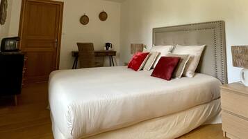 A neatly arranged bedroom with a large bed, a wooden desk, and a chair.
