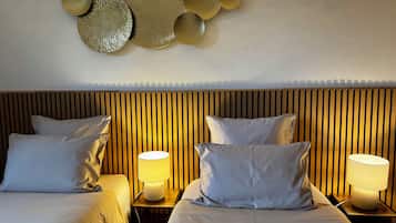 A hotel room with two beds, each with a pillow and a bedside lamp.