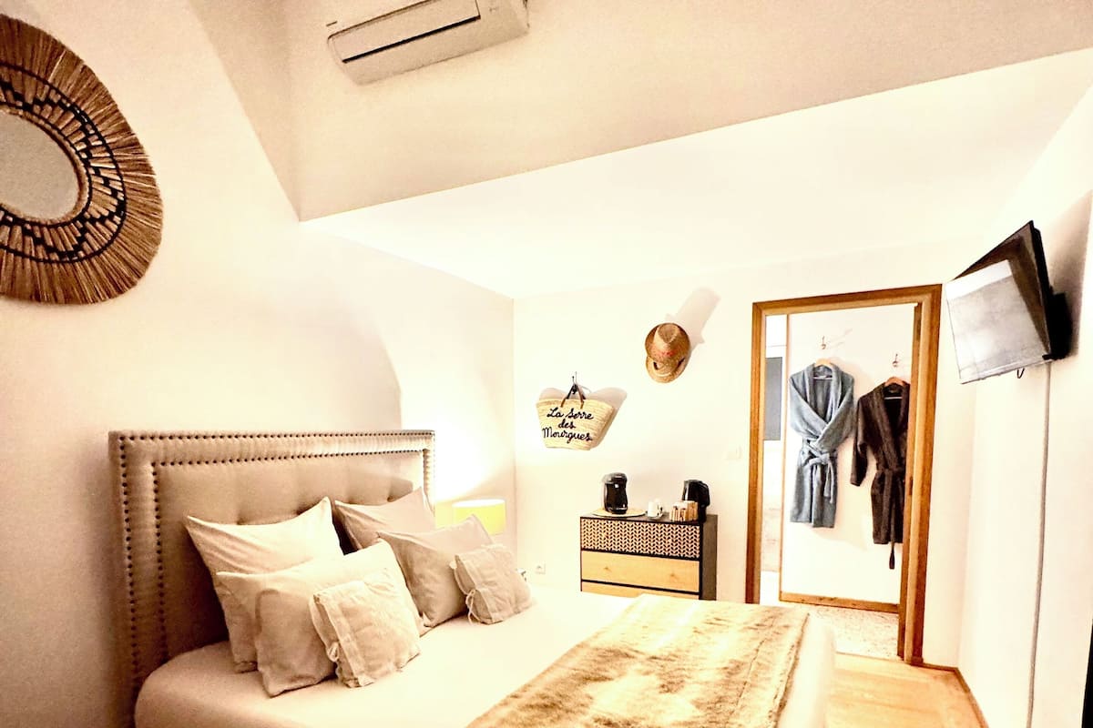 A bedroom with a large bed, a nightstand, a mirror, and a wardrobe.