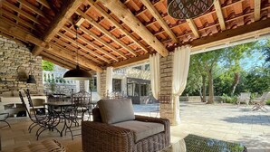 An outdoor patio with wicker furniture, a stone wall, and a wooden ceiling. - La Serre des Mourgues (Méjannes-lès-Alès)