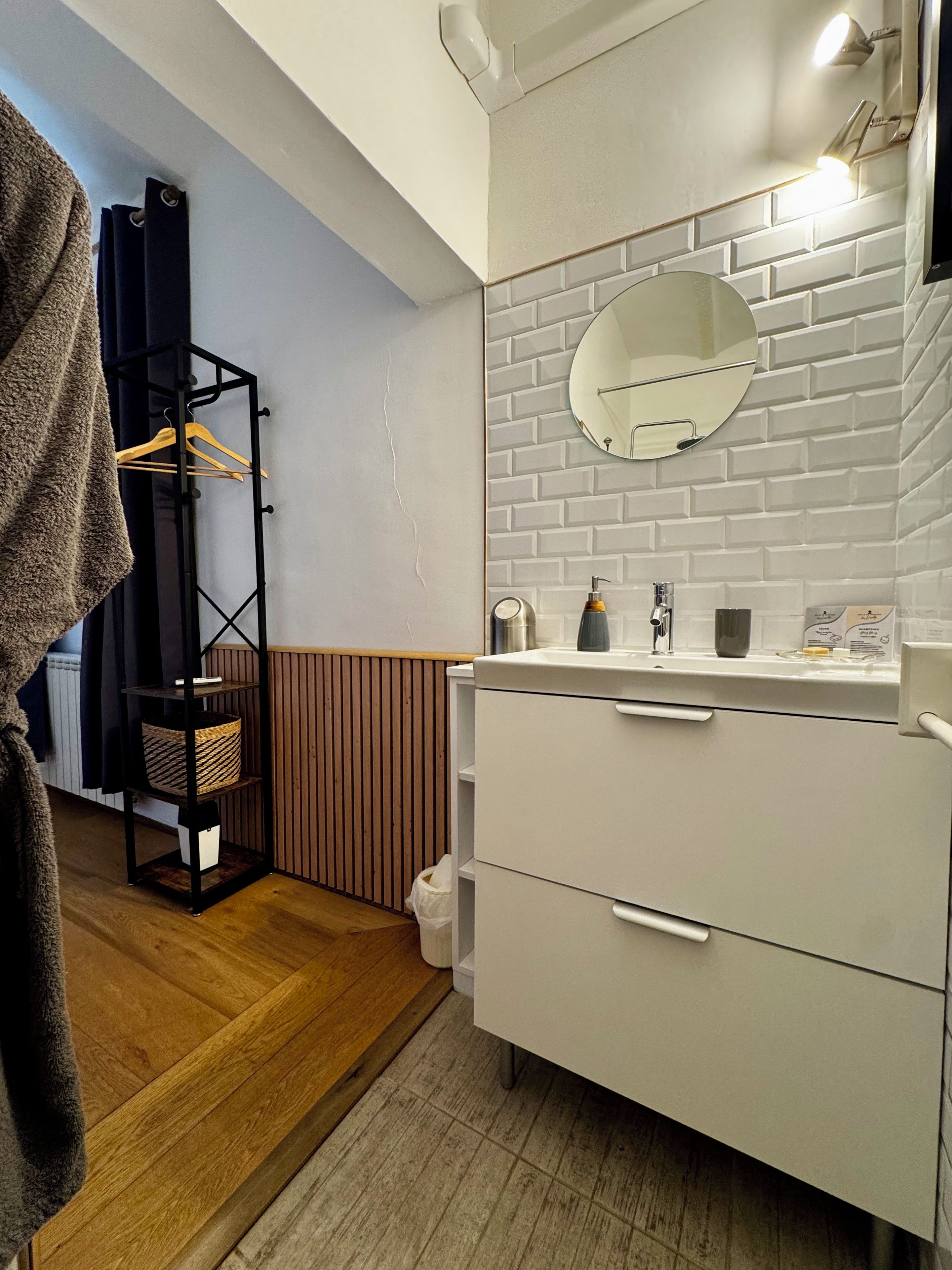 A bathroom with a white vanity, a mirror, and a towel rack.