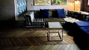 A cozy living room with a herringbone wooden floor, a striped sofa, and two paintings on the wall. - Florence from above (Firenze)