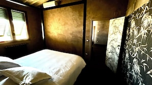 A room with a bed, a radiator, a window with blinds, and a door leading to another room. - Florence from above (Firenze)