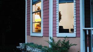 Uma casa com duas janelas, uma delas com uma lâmpada visível no interior.
