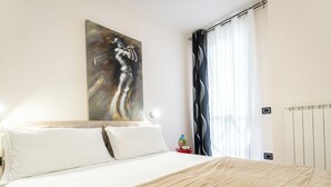 Een hotelkamer met een groot bed, een schilderij aan de muur en een raam met gordijnen.