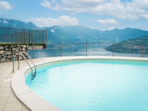 Une piscine avec vue sur les montagnes et un mur en pierre.