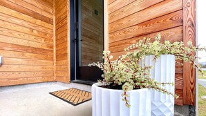 Eine Holzfassade mit einem weißen Blumenkasten und einem grünen Gefäß mit weißen Steinen.