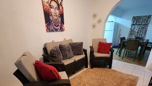 A living room with a sofa set, a coffee table, and a rug. There is a painting on the wall and a dining area in the background. - LAKE HOUSE- Adames Lake House (San Sebastián)