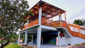 A two-story building with a covered balcony and a staircase leading to the upper level. - LAKE HOUSE- Adames Lake House (San Sebastián)