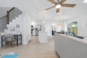 Un soggiorno moderno con una scala, una cucina e un'area pranzo.