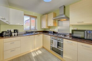 Equipped with a gas stove, oven, and microwave, this kitchen offers a clean and contemporary cooking space.