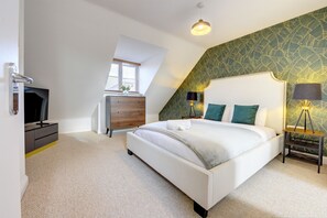Cozy attic-style room with a large bed, bedside tables, and a mounted TV.